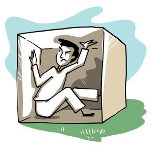 Un homme enfermé dans une boite de forme cubique, il pousse avec ses deux mains et un pied, les parois du haut et de côtés, une expression agacée traverse son visage